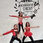 Three Roundabout Circus students perform a three person pyramid in front of the Roundabout Circus sign at the studio in Wyoming.